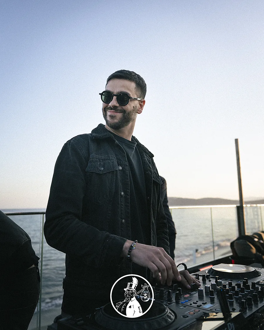 Raffaele Sanna in consolle al tramonto sul mare, con occhiali da sole